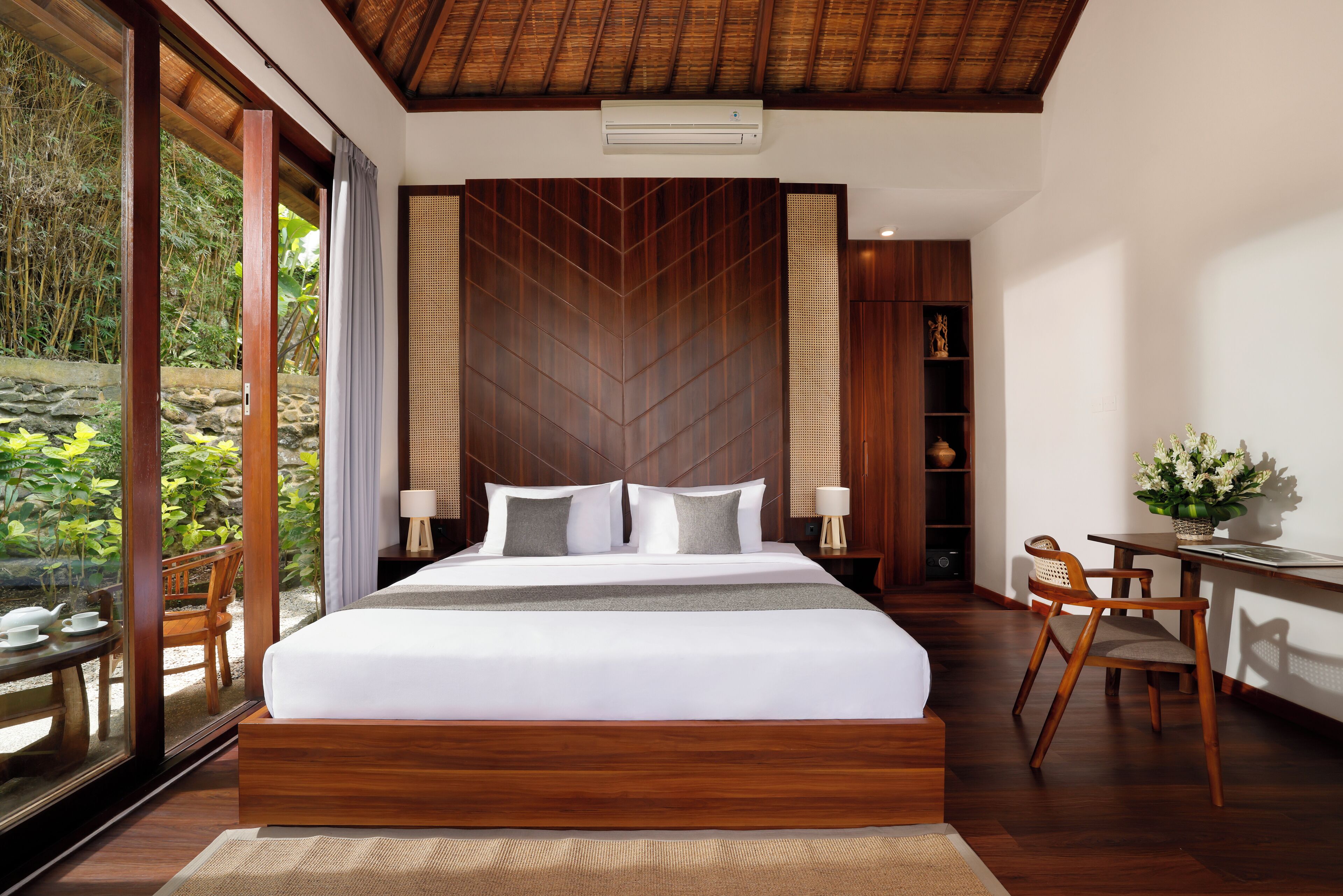 Un dormitorio moderno con una cama grande, cabecero de madera y vistas a zonas verdes.