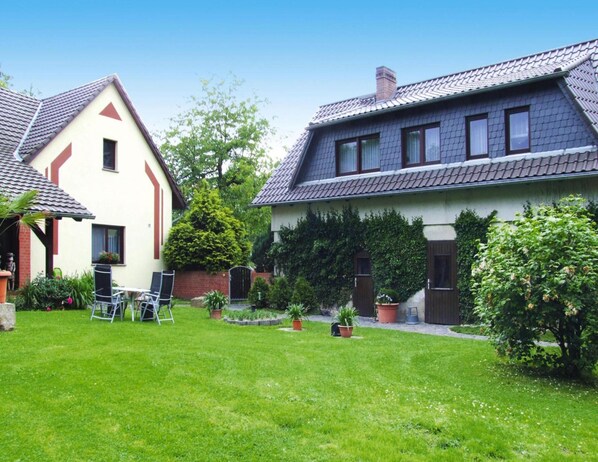 A residential property with a well-maintained lawn, a patio area with outdoor furniture, and a garden with various plants and a small tree. - Apartment Near Altdobern Castle & Spreewald (Altdöbern)