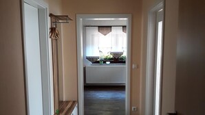 Pasillo que conduce a una cocina con un radiador, suelo de madera y una planta colgante.