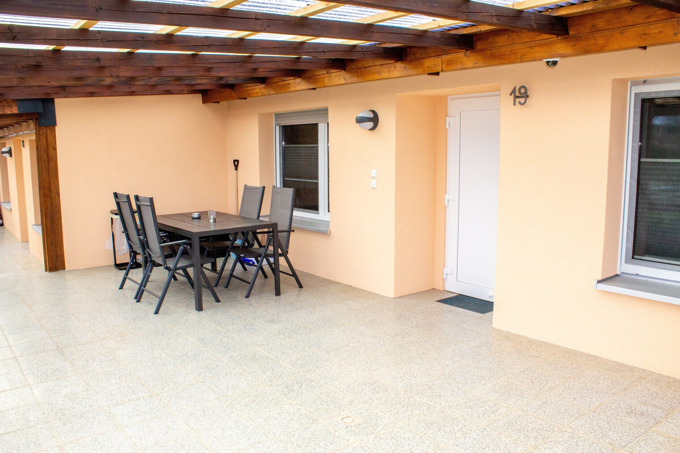 A room with a tiled floor, a table with chairs, a door, and a window.