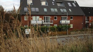 A two-story residential building with multiple windows, a balcony, and solar panels on the roof. - Ferienwohnung, St. Peter - Ording (St. Peter-Ording)