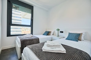 A hotel room with two beds, a window, a nightstand, and a lamp.