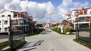 A residential street with houses, a paved walkway, and a gated entrance. - Apartment im Avalon Hotel Bellevue (Fehmarn)
