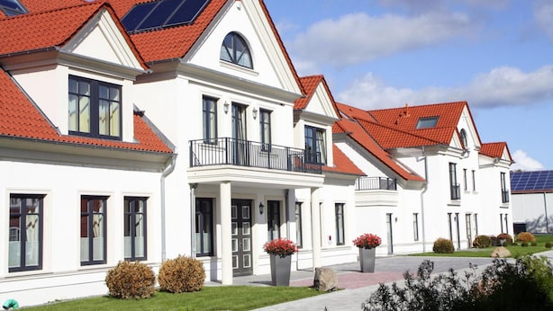 A row of white houses with red roofs and solar panels, featuring balconies and a well-maintained lawn. - Apartment im Avalon Hotel Bellevue (Fehmarn)