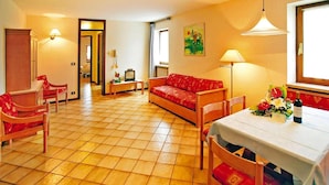 A cozy living room with a sofa, chairs, a dining table, and a TV. - Residence La Filanda in Costermano (Costermano sul Garda)