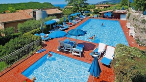 A large outdoor swimming pool with multiple lanes, surrounded by lounge chairs and umbrellas. - Residence La Filanda in Costermano (Costermano sul Garda)