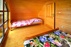Una pequeña habitación de madera con una cama individual y un armario.