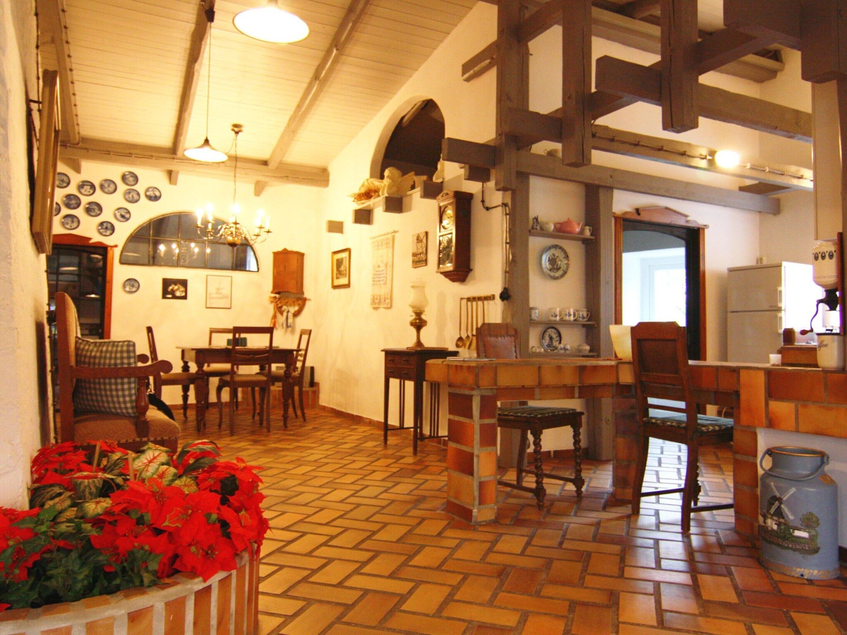 A cozy kitchen with wooden beams, a dining area with chairs, a refrigerator, and a sink.