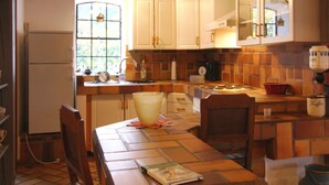 A kitchen with white cabinets, a window, a sink, a stove, and a table with a book. - Detached Holiday Home in Medelby (Medelby)