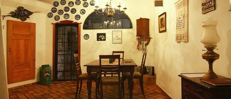 Un comedor con una mesa y sillas, una araña y una pared decorada con platos y fotografías.