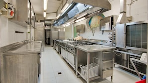 A commercial kitchen with stainless steel appliances, a large oven, and a food display unit.