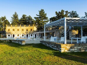 En innergård med en pool, utomhusmöbler och en byggnad i sten med valv.