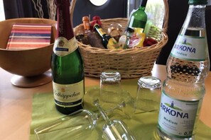 A table with a bottle of Rotkappchen, a basket of snacks, and a bottle of Arkona water. - Ferienhaus Muritzhus an der Muritz (Röbel/Müritz)