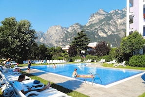 A swimming pool with lounge chairs and a mountain backdrop.