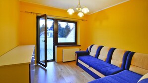 A bright room with yellow walls, a large window, and a blue sofa. - Comfy Lakeside House With Private Garden (Ińsko)