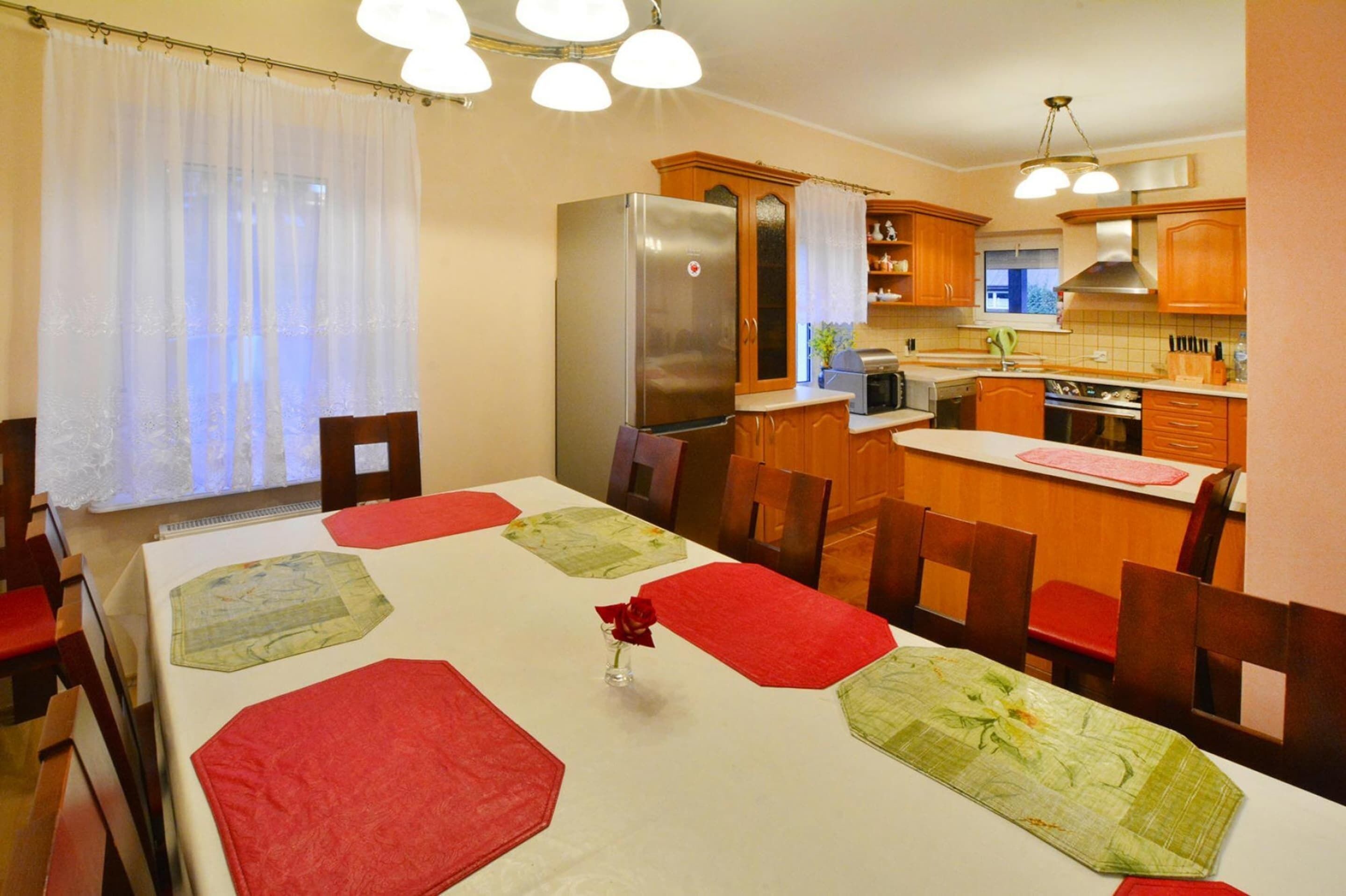 A dining area with a table set for four, a refrigerator, and wooden cabinets in the background.