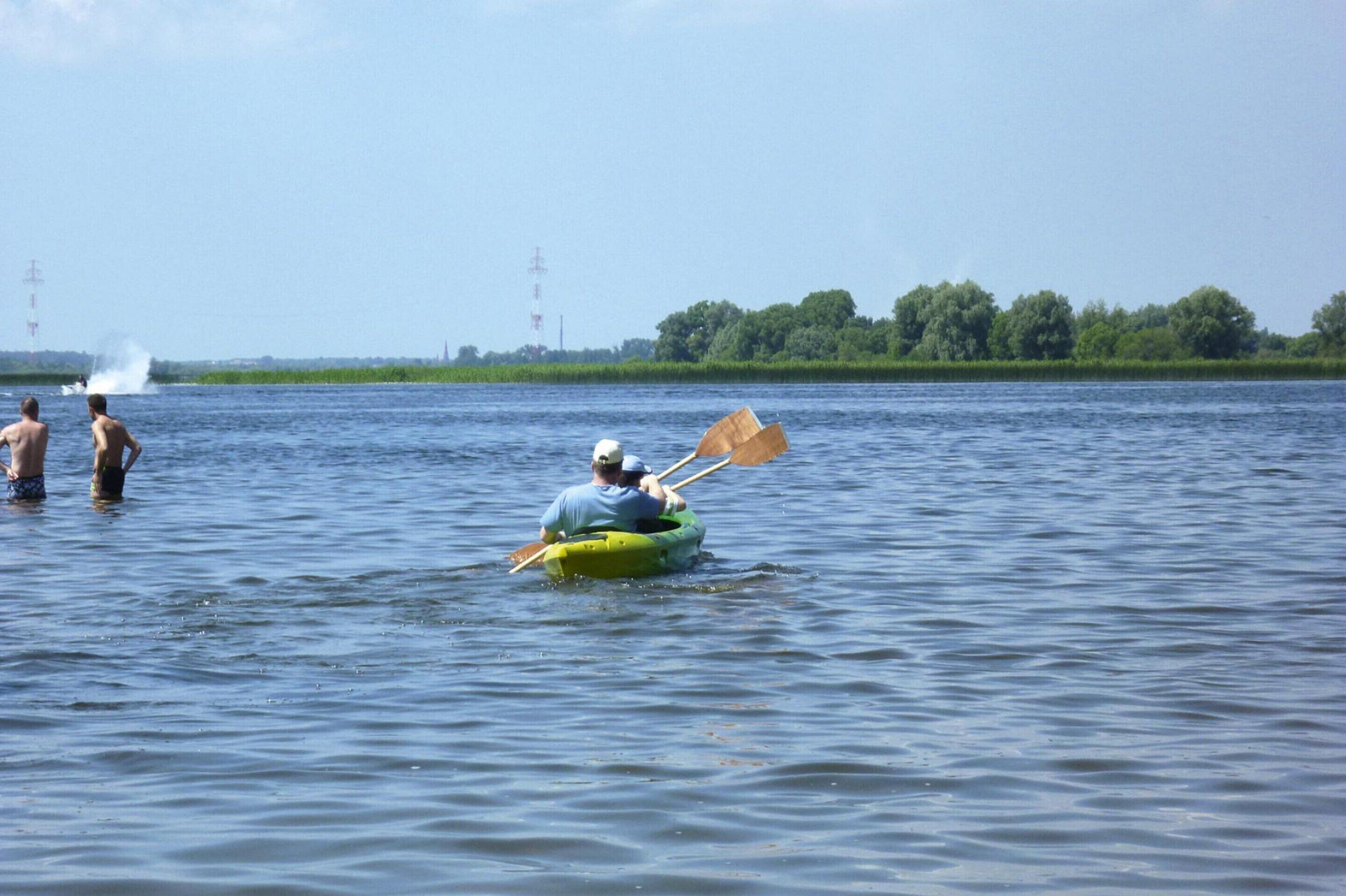 Eine Person sitzt in einem grünen Kajak auf ruhigem Wasser.