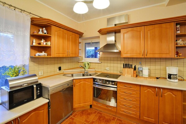 A kitchen with wooden cabinets, a stainless steel microwave, a stove, and a coffee maker.
