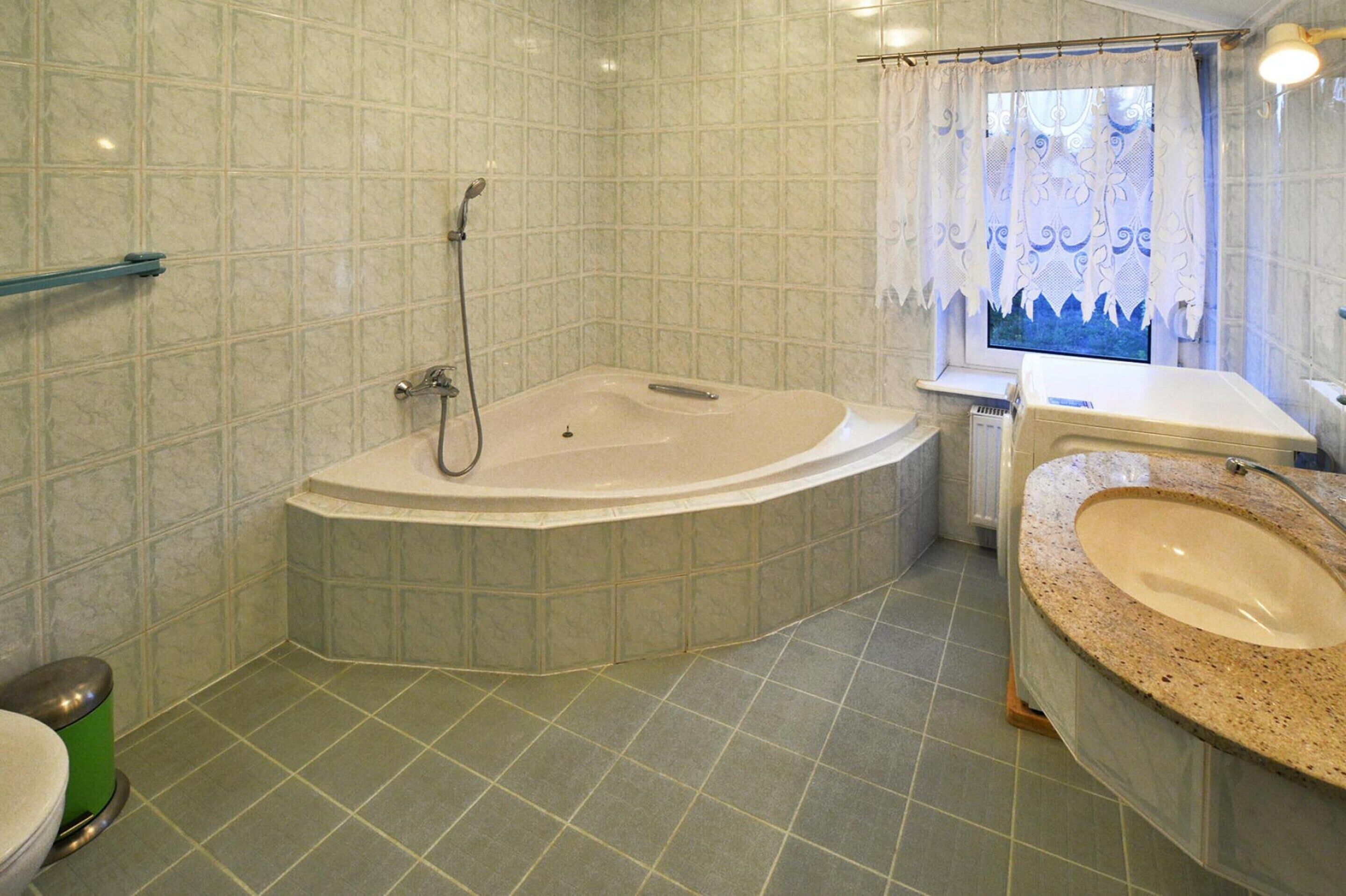 Une salle de bain avec une baignoire sur pieds, un lavabo avec un plan de toilette en granit et des toilettes.