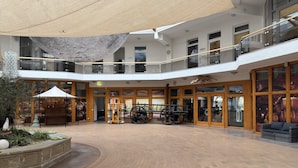 A spacious atrium with a brick floor, wooden benches, and a covered seating area. - Residence Park am Schweriner See, Schwerin (Raben Steinfeld)