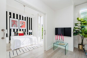 Un dormitorio moderno con una cama, mesita de noche y televisión montada en la pared.