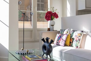 A modern living room with a glass coffee table, a black vase, and a sofa with colorful pillows. - Art Suite Granada (Granada)