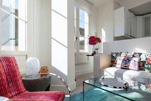 A modern living room with a glass coffee table, a red armchair, and a sofa with colorful cushions. - Art Suite Granada (Granada)