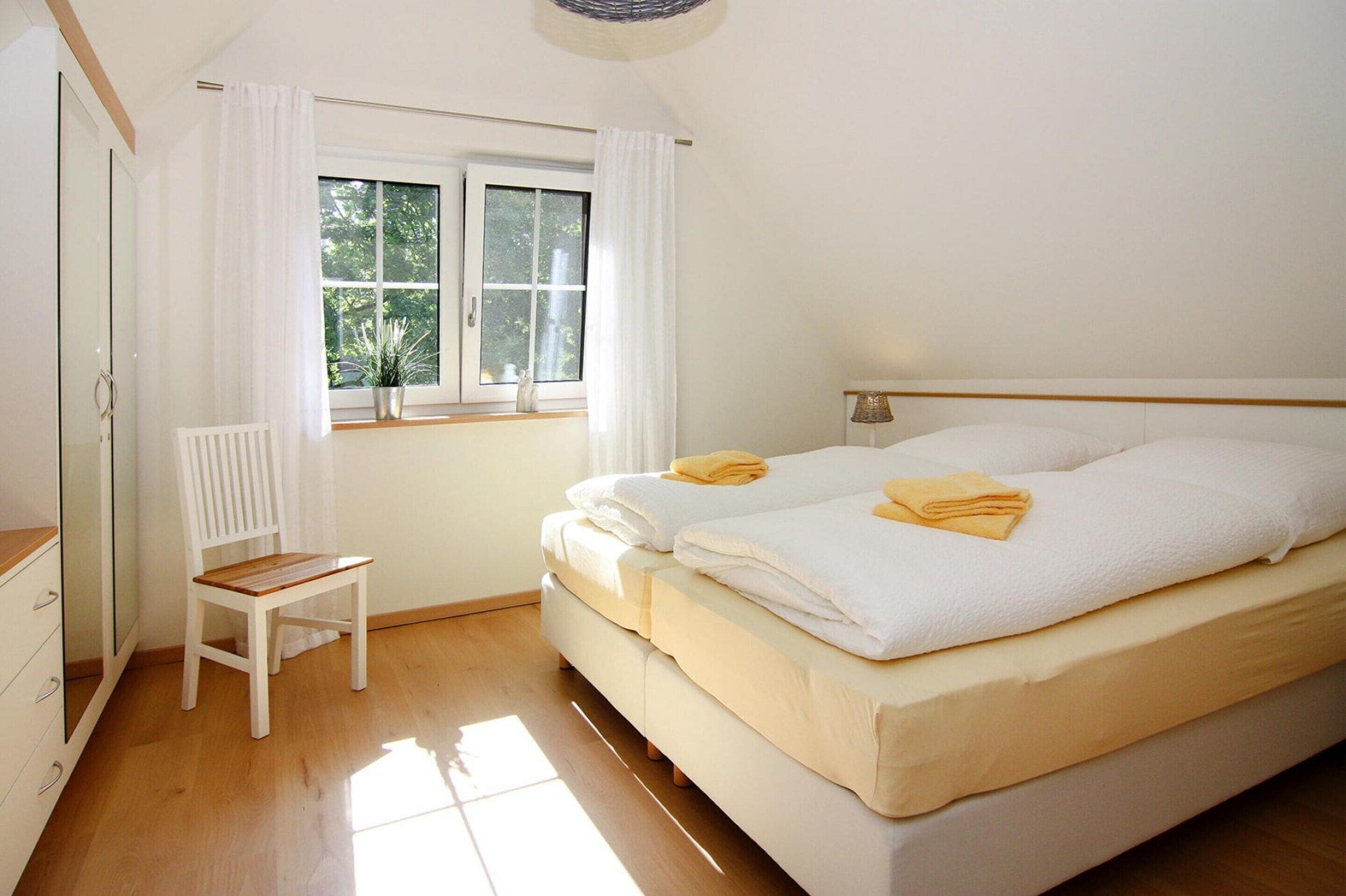 A bedroom with a bed, a chair, a window, and a radiator.