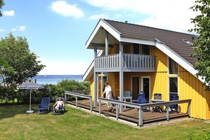 A yellow building with a balcony, outdoor seating, and a view of the sea. - Holiday Park Muritz, Rechlin-nord (Rechlin)