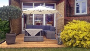 A patio with a sectional sofa, a table, and an umbrella. - Hollaender Windmuehle in Neubukow (Neubukow)