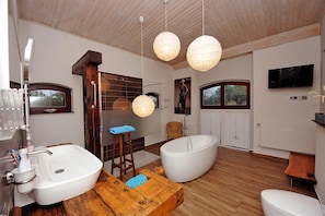 Een moderne badkamer met een vrijstaand bad, een wastafel en een houten kruk.