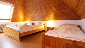 A bedroom with two wooden beds, a window, and a radiator. - Ferienwohnung in Westerland auf Sylt (Sylt)