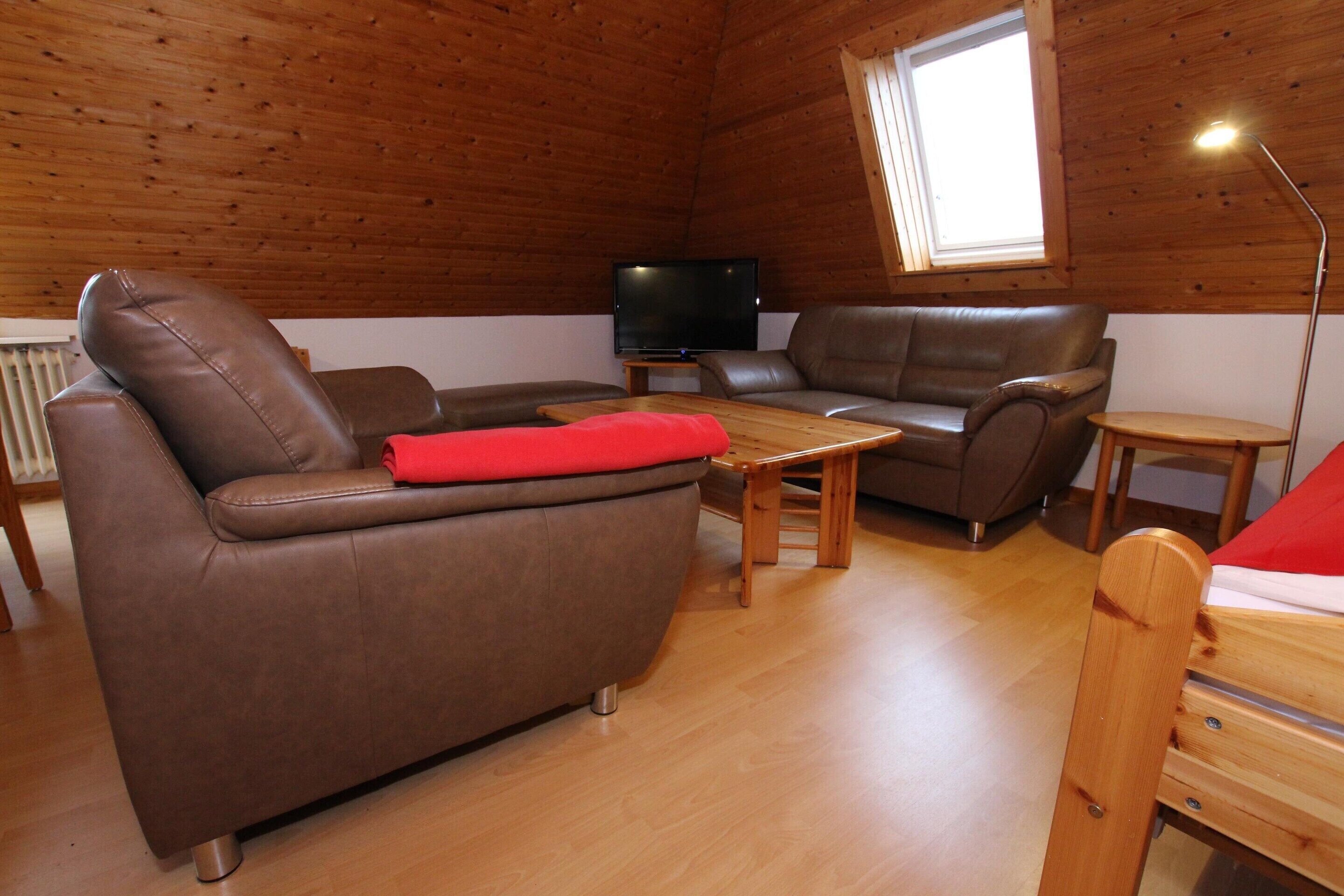 Una habitación acogedora con un sofá de cuero marrón, una mesa de centro de madera y un televisor.