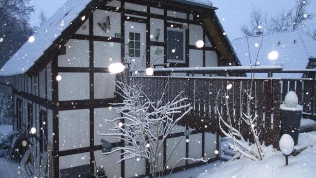 A traditional half-timbered house with a snow-covered roof and a butterfly decoration on the wall. - Ferienwohnung in Frankenau (Frankenau)