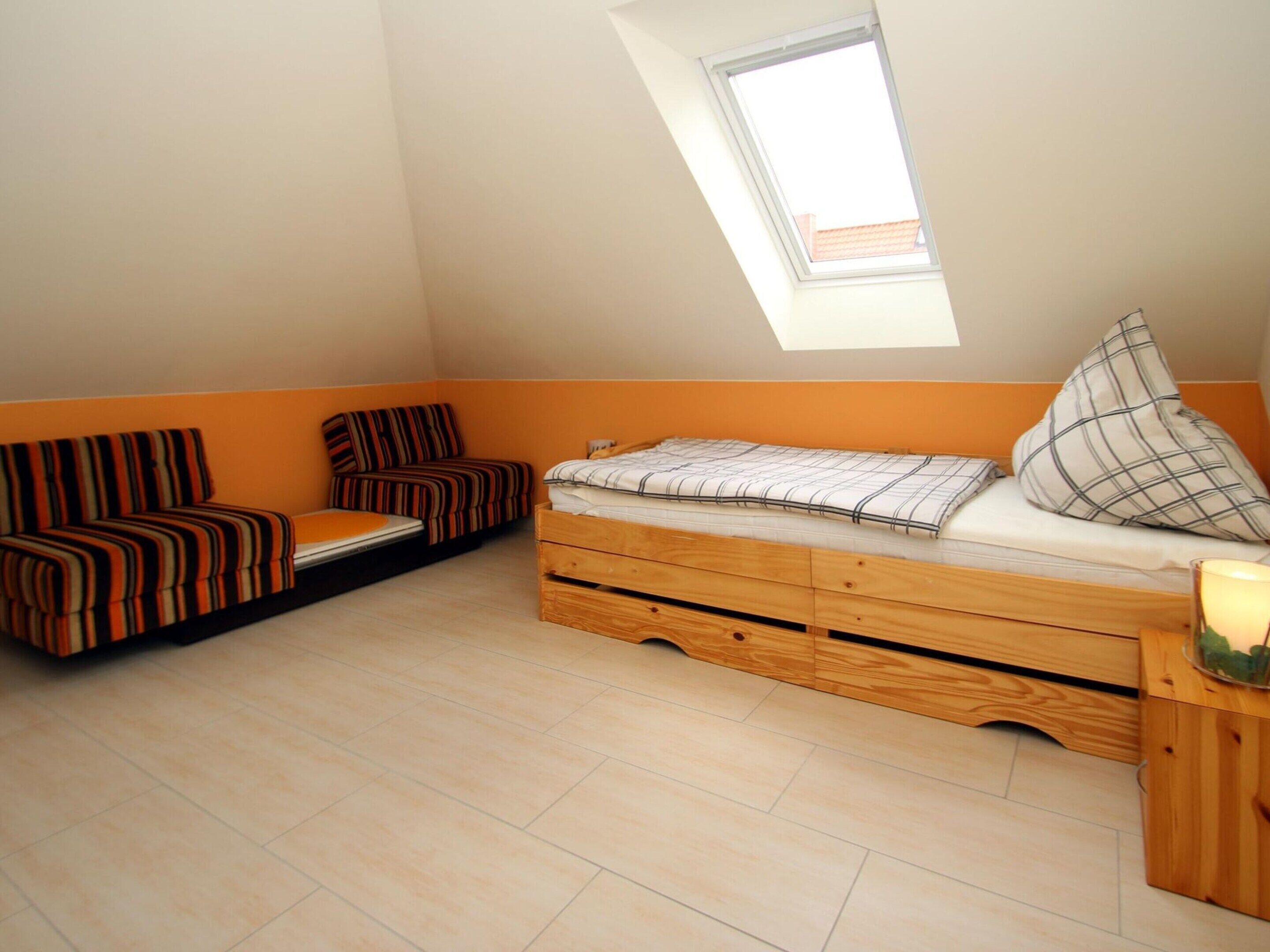Een compacte kamer met een hoogslaper, twee slaapbanken, een klein tafeltje en een dakraam.