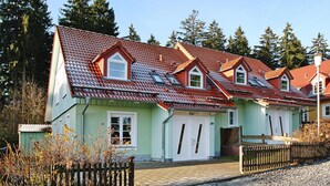 A row of houses with red-tiled roofs and light green walls, surrounded by trees. - Ferienhauser im Tannenpark, Tanne (Oberharz am Brocken)