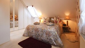 A bedroom with a bed, two bedside lamps, a mirror, and a red rug. - Ferienwohnung Goehrenz bei Leipzig-markranstaedt (Markranstaedt)