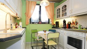 A kitchen with a dining table, chairs, a sink, and cabinets. - Ferienwohnung Goehrenz bei Leipzig-markranstaedt (Markranstaedt)