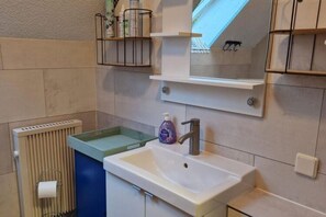 A bathroom with a sink, mirror, and towel rack. - Ferienwohnung in Frankenau (Frankenau)