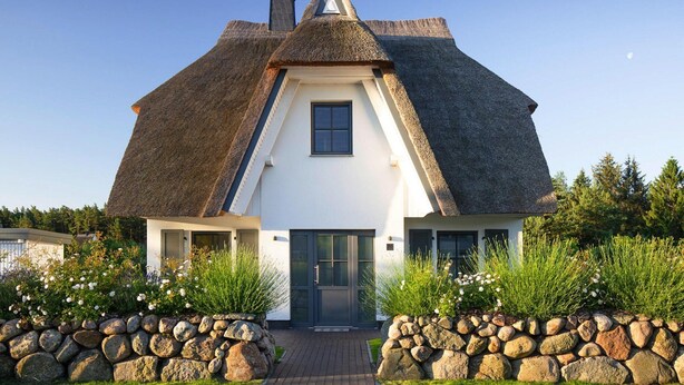 A house with a steeply pitched roof, white walls, and a dark-colored door. - Ferienhaus, Fuhlendorf (Fuhlendorf)