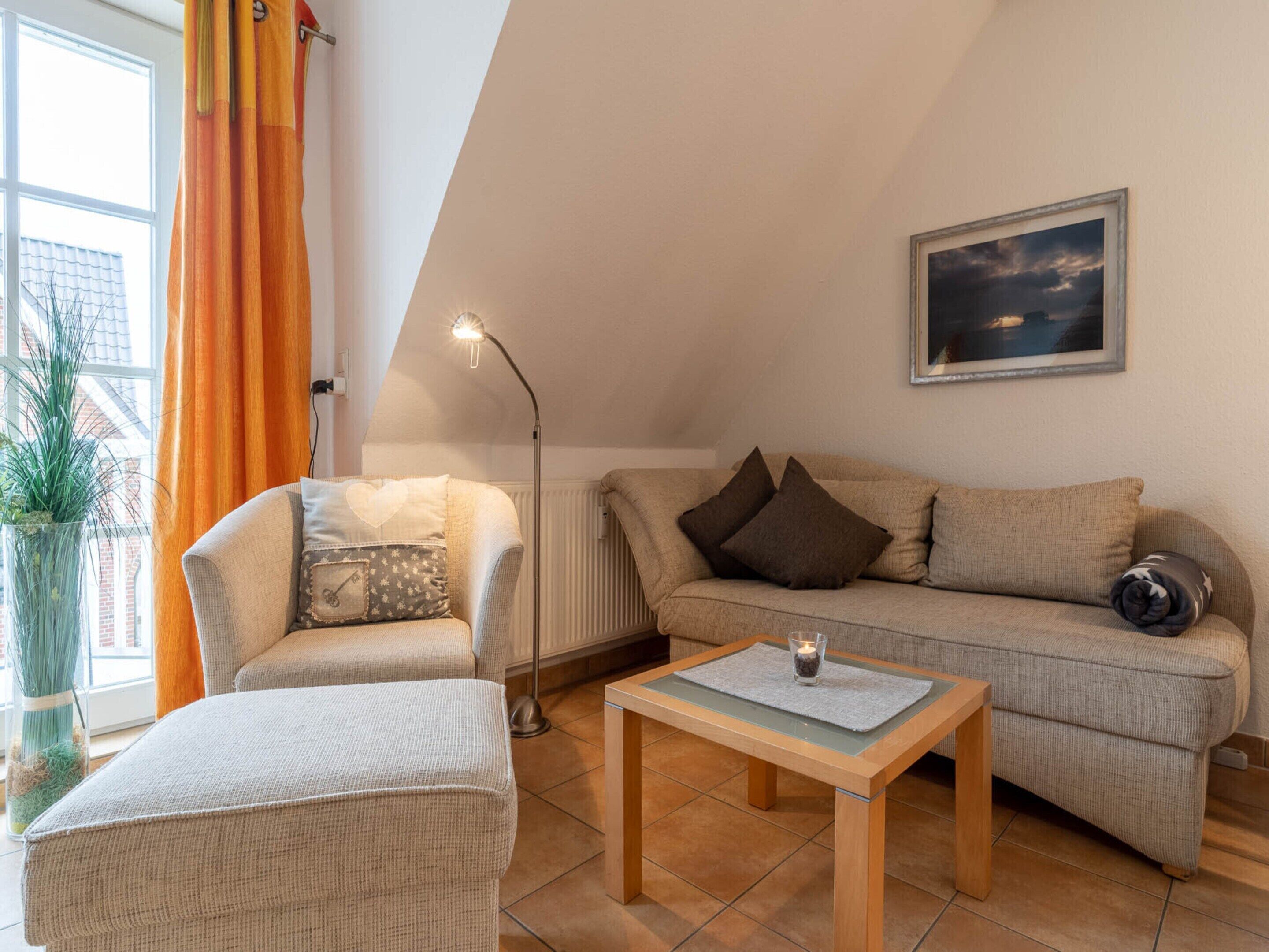 A cozy living room with a sofa, armchair, and a small table.