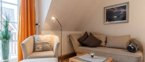 A cozy living room with a sofa, armchair, and a small table.