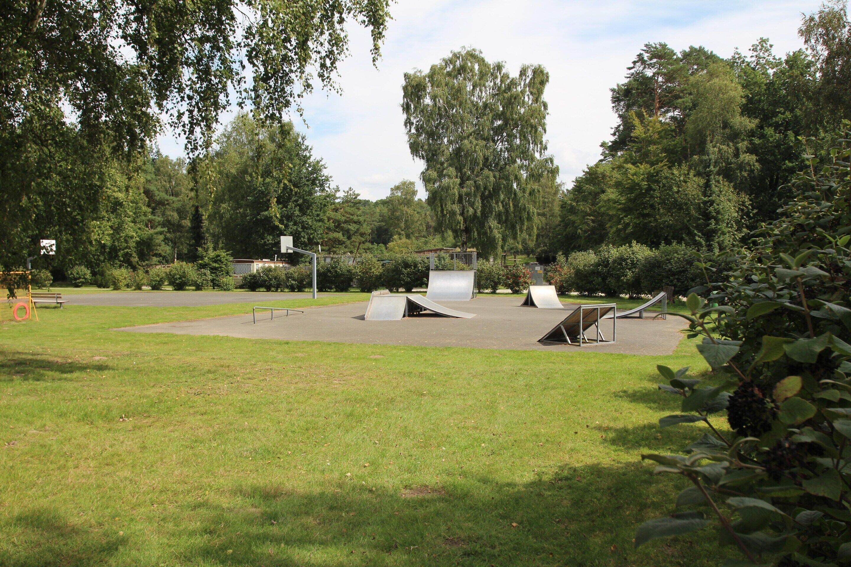 A park with a playground area featuring metal ramps and a slide.