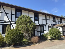 Un edificio tradicional con entramado de madera y fachada simétrica, con múltiples ventanas y un pequeño porche.