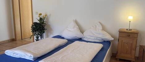 A neatly made bed with white linens, a bedside table with a lamp, and a framed picture on the wall.