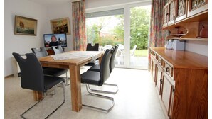 A dining area with a wooden table, black chairs, and a television on the wall. - Bungalow Near Dornumersiel Beach (Dornum)