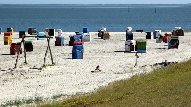 A beach with numerous colorful containers and a few people. - Bungalow Near Dornumersiel Beach (Dornum)
