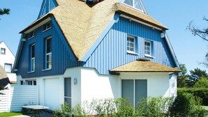 A house with a steeply pitched roof, blue exterior walls, and a thatched roof section. - Semi-detached House, Zingst (Zingst)