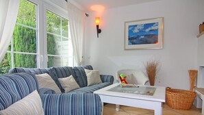 A living room with a striped sofa, a glass coffee table, a wicker basket, and a framed picture on the wall. - Semi-detached House, Zingst (Zingst)