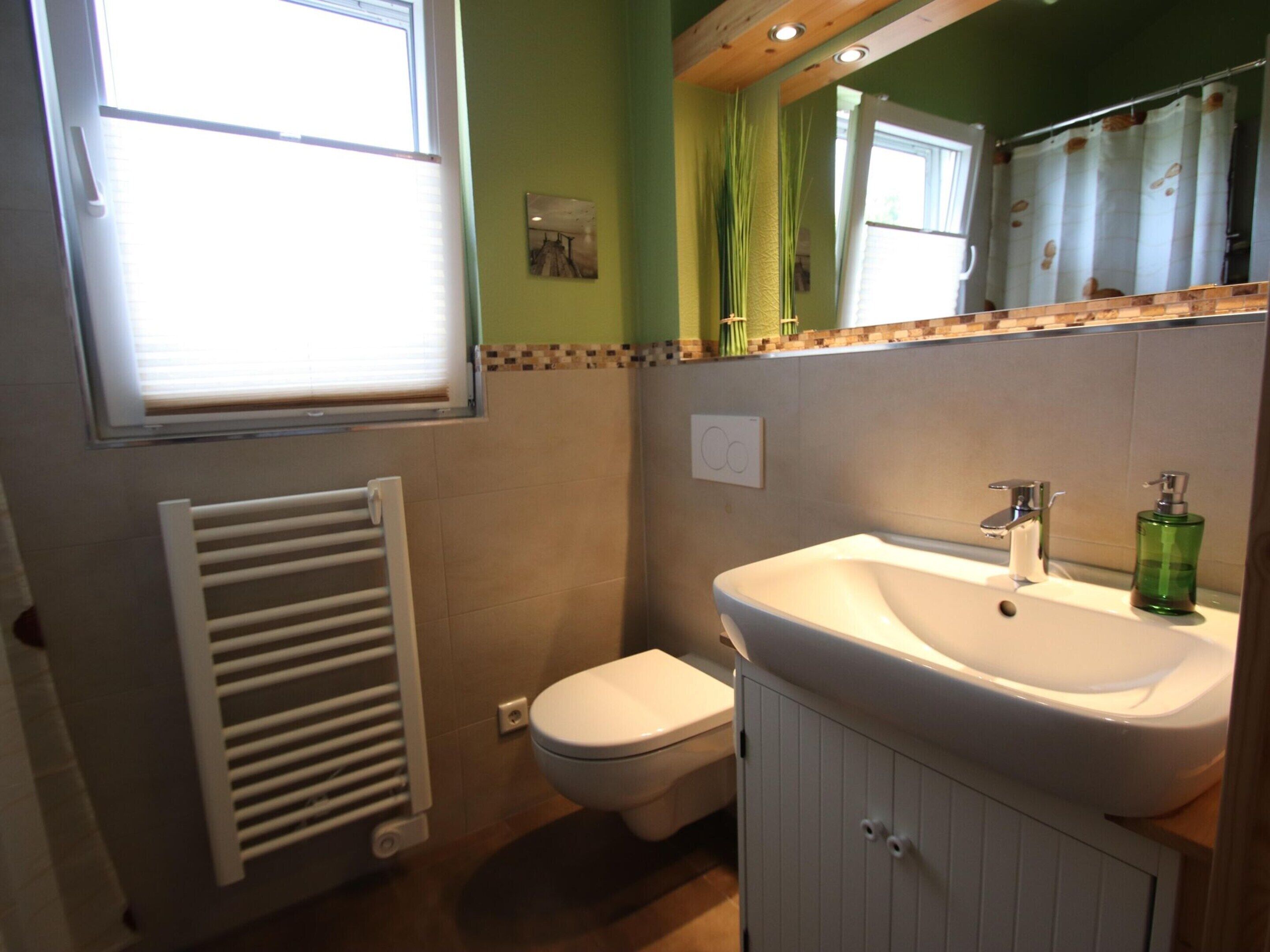 A bathroom with a toilet, sink, and radiator.